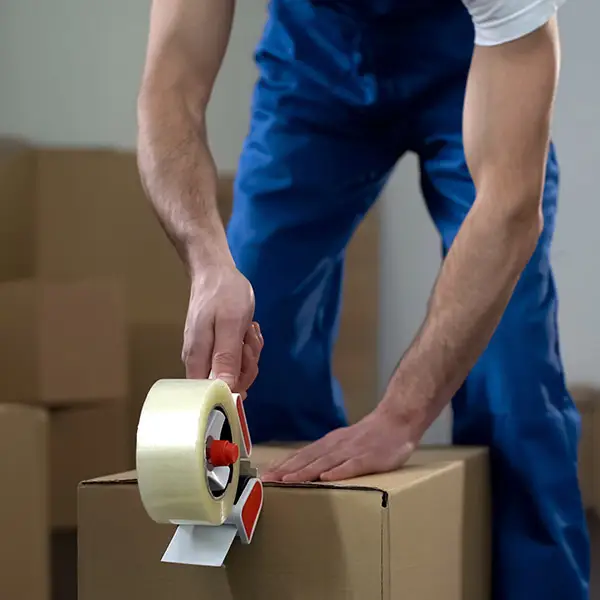Ein Möbelpacker-Profi beim Verpacken eines Umzugskartons
