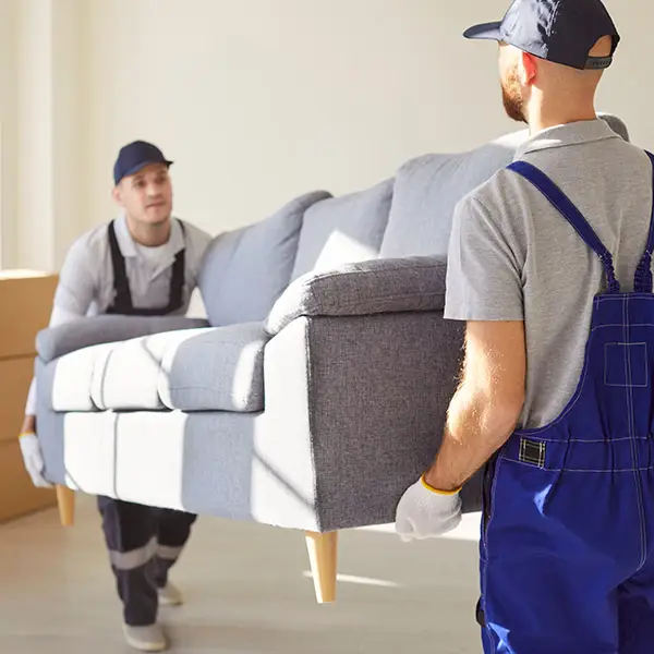 Zwei Möbelpacker tragen eine Couch aus einem Wohnzimmer