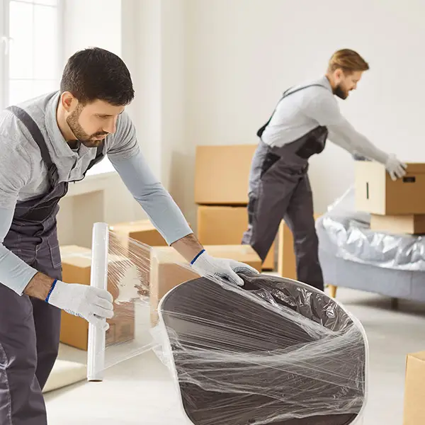 Zwei Umzugshelfer beim Verpacken von Möbelstücken und Umzugskartons